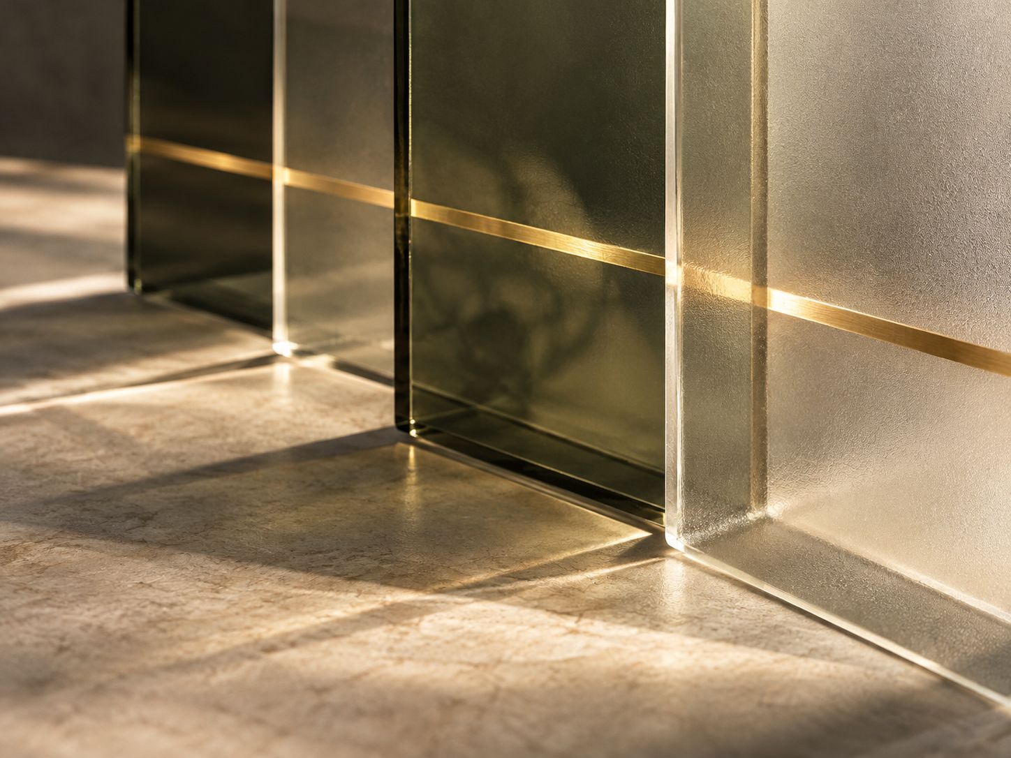 Conceptual still life of translucent olive glass layers with an aligned brass highlight.